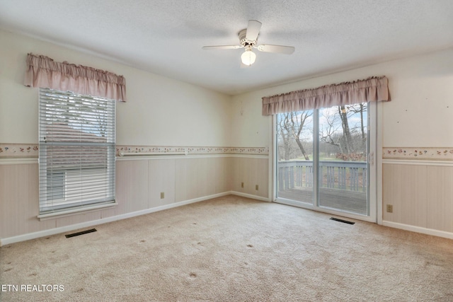 carpeted empty room with ceiling fan and a textured ceiling