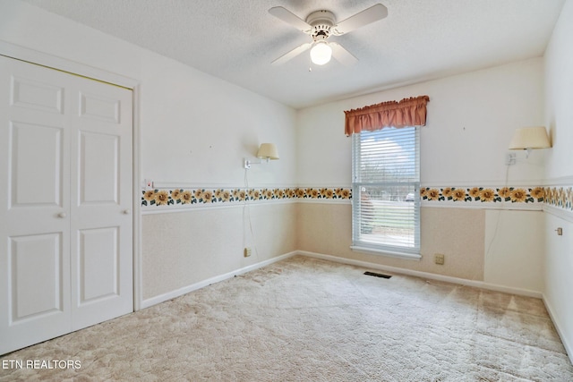 empty room with a textured ceiling, light colored carpet, and ceiling fan