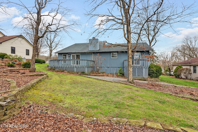 rear view of property featuring a yard and a wooden deck