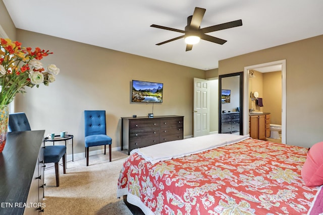 carpeted bedroom with ensuite bath and ceiling fan