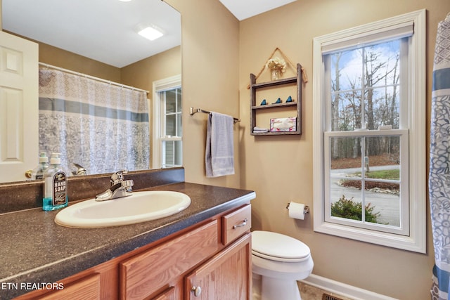 bathroom with plenty of natural light, vanity, and toilet