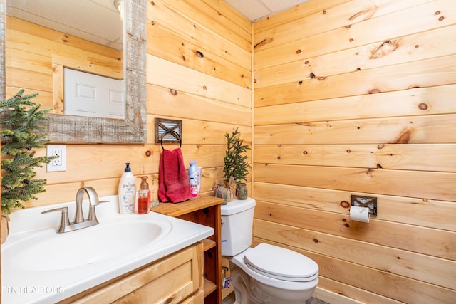 bathroom featuring wood walls, vanity, and toilet