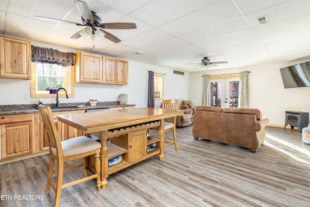 kitchen featuring a paneled ceiling, wood-type flooring, a wood stove, and french doors