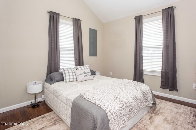 bedroom with electric panel, hardwood / wood-style floors, and lofted ceiling