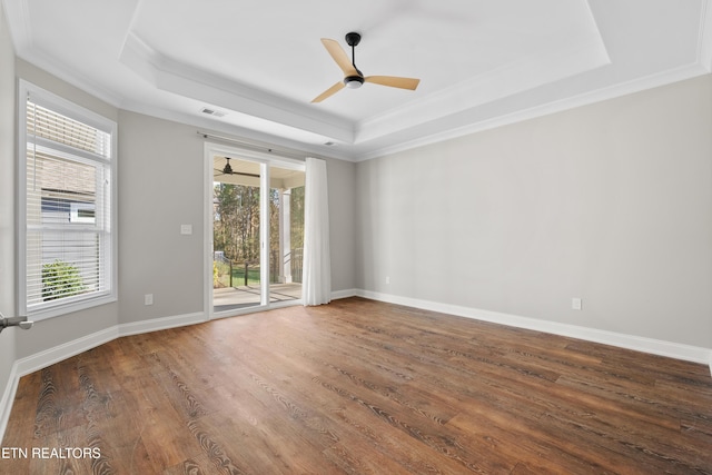 empty room featuring a tray ceiling, dark hardwood / wood-style floors, ornamental molding, and ceiling fan