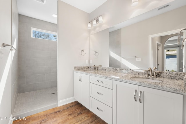 bathroom featuring tiled shower, vanity, and hardwood / wood-style flooring