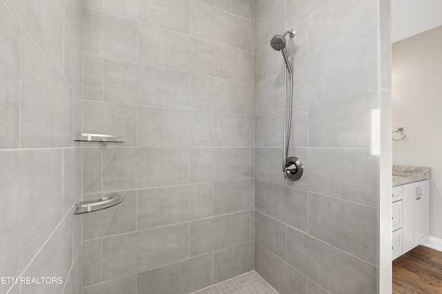 bathroom featuring tiled shower, hardwood / wood-style floors, and vanity