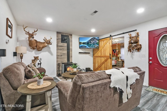 living room featuring a barn door, dark hardwood / wood-style floors, and a wood stove