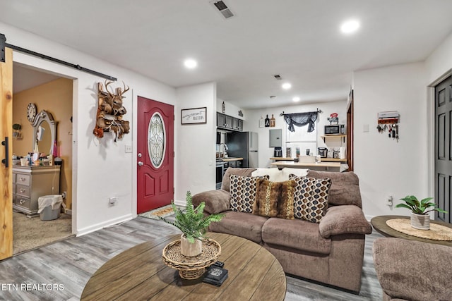 living room with light wood-type flooring, a barn door, and electric panel