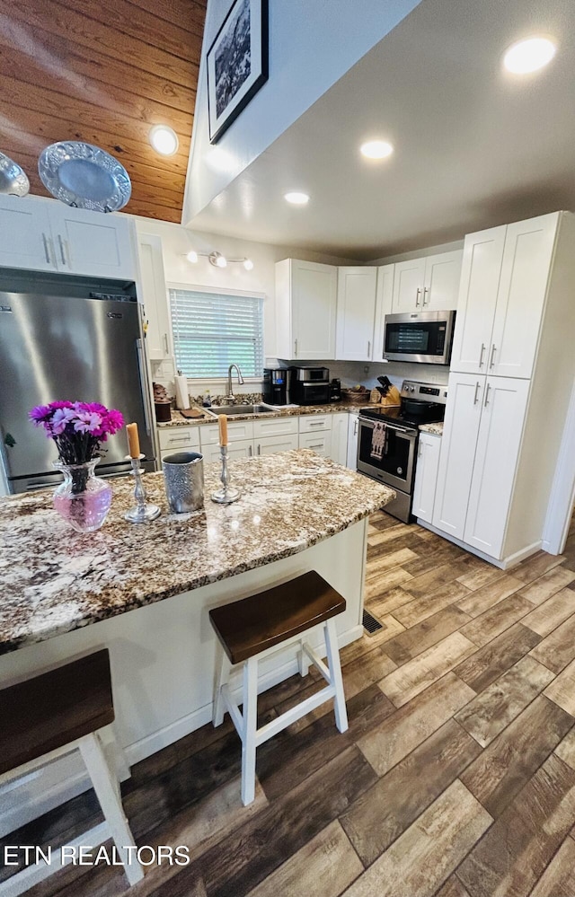 kitchen featuring appliances with stainless steel finishes, a breakfast bar, sink, and white cabinets