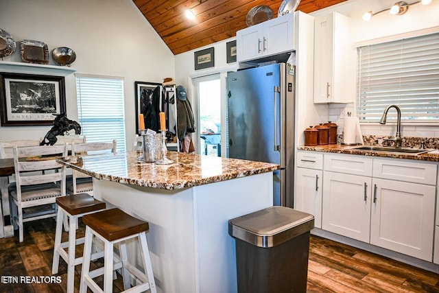 kitchen with sink, stone countertops, a kitchen island, high quality fridge, and white cabinets