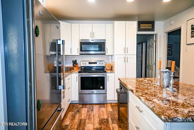 kitchen with white cabinetry, stainless steel appliances, dark hardwood / wood-style flooring, light stone countertops, and decorative backsplash