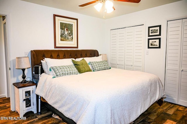 bedroom with ceiling fan, dark hardwood / wood-style flooring, and two closets