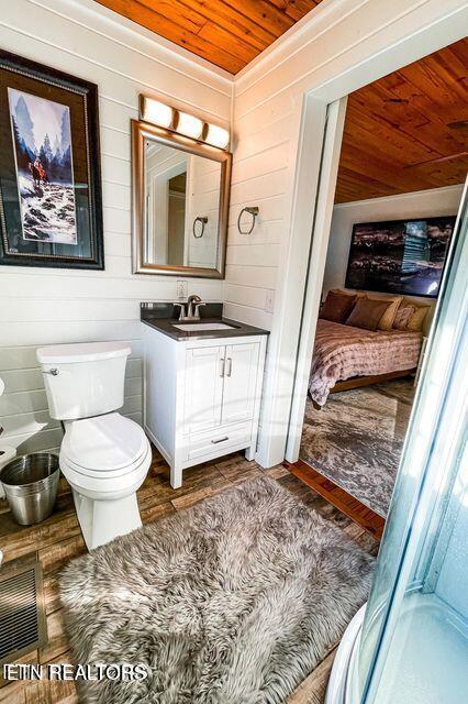 bathroom featuring wood walls, vanity, wood ceiling, and toilet