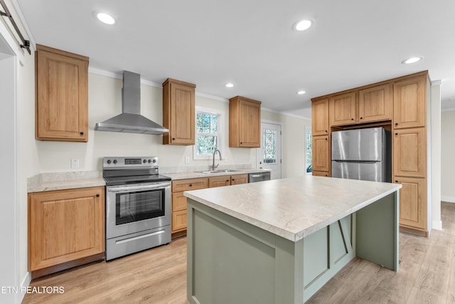 kitchen with sink, wall chimney range hood, crown molding, a kitchen island, and appliances with stainless steel finishes