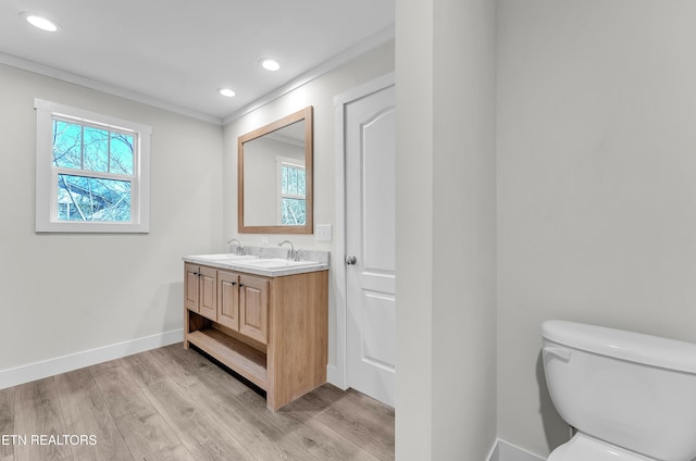 bathroom with hardwood / wood-style floors, vanity, toilet, and ornamental molding