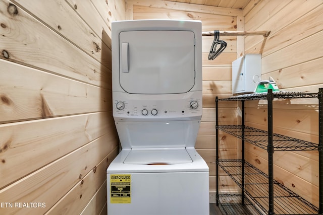 washroom featuring stacked washer and dryer, laundry area, and wooden walls