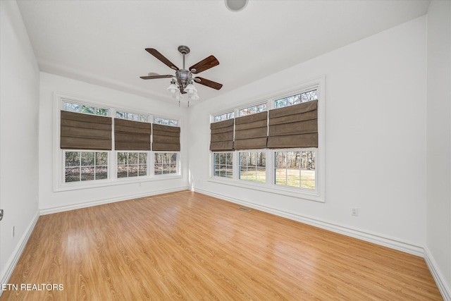 spare room with ceiling fan, light wood-type flooring, and a wealth of natural light