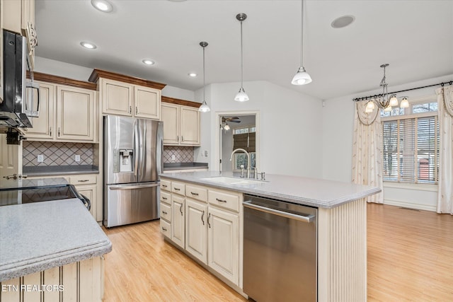 kitchen with sink, stainless steel appliances, backsplash, an island with sink, and pendant lighting