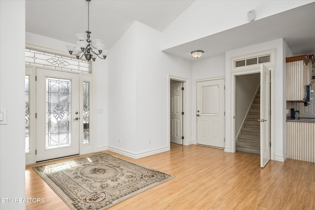 entryway with lofted ceiling, light hardwood / wood-style floors, plenty of natural light, and a notable chandelier