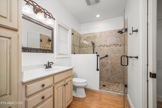 bathroom featuring wood-type flooring, vanity, toilet, and a shower with door