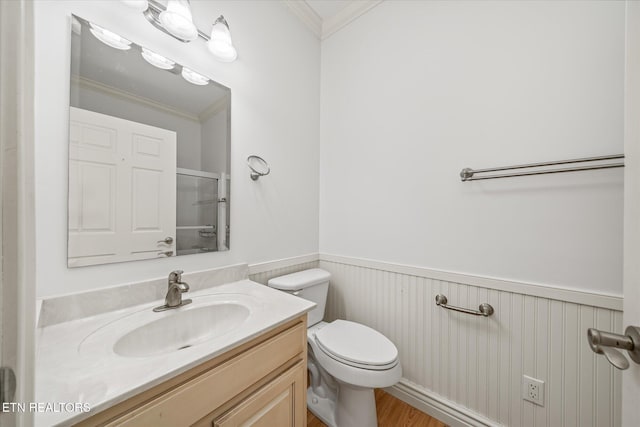 bathroom with toilet, vanity, a shower with shower door, and ornamental molding