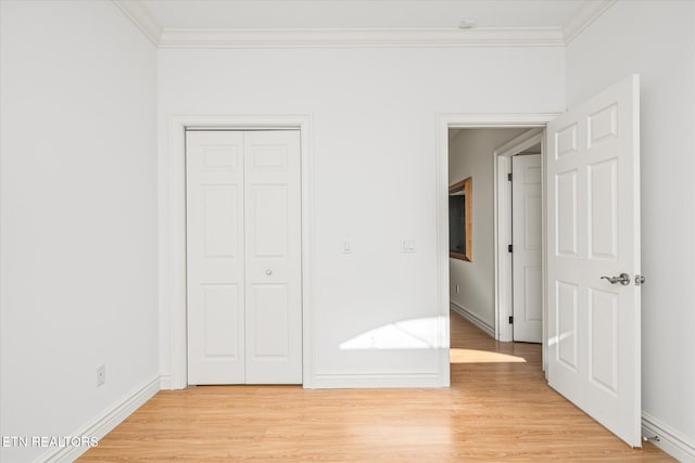 unfurnished bedroom with light hardwood / wood-style floors, ornamental molding, and a closet