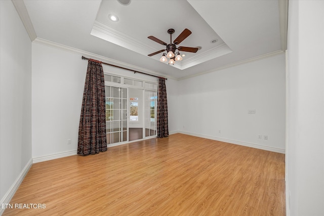 empty room featuring ornamental molding, light hardwood / wood-style flooring, and a tray ceiling