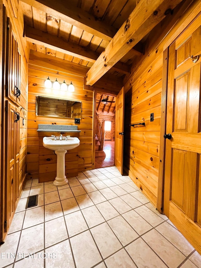 bathroom with beamed ceiling, tile patterned flooring, wooden walls, and wood ceiling