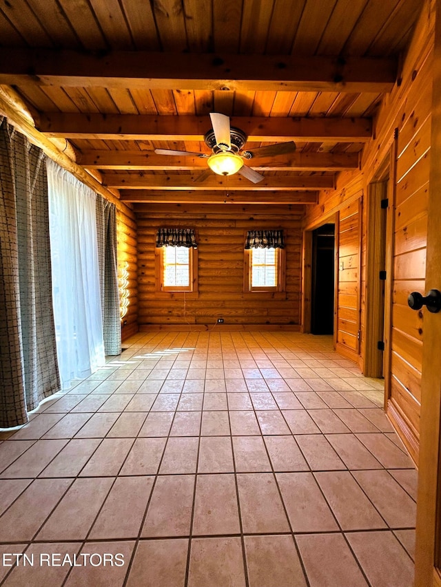 tiled empty room with beam ceiling, rustic walls, ceiling fan, and wood ceiling