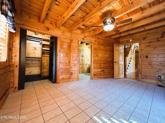 spare room featuring ceiling fan, beam ceiling, light tile patterned floors, wooden ceiling, and wood walls