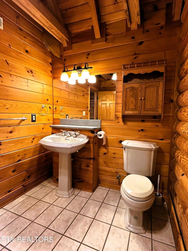 bathroom with beam ceiling, wooden walls, and tile patterned flooring