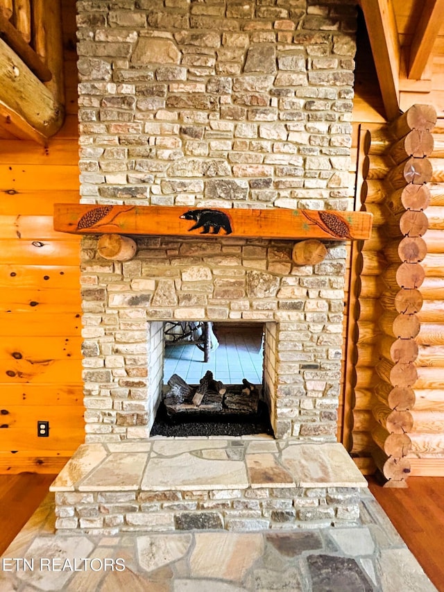 room details with a fireplace, log walls, and hardwood / wood-style flooring