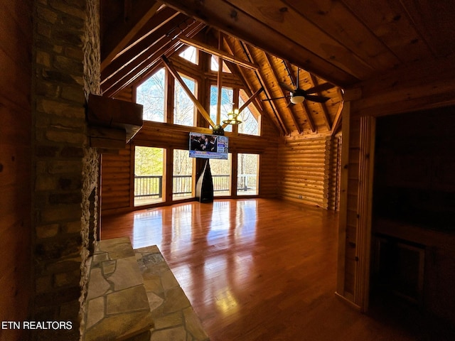 unfurnished living room with wood ceiling, ceiling fan, log walls, high vaulted ceiling, and beamed ceiling