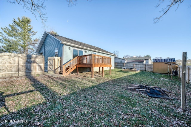 back of house with a shed, a yard, and a wooden deck