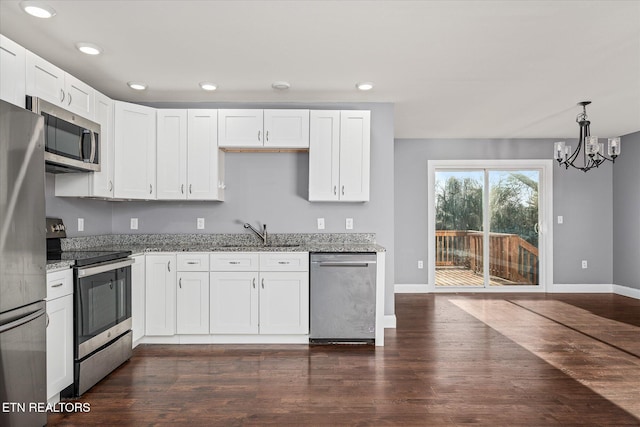 kitchen featuring sink, stainless steel appliances, light stone counters, pendant lighting, and white cabinets