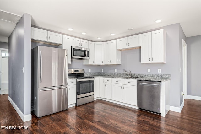 kitchen with light stone countertops, white cabinetry, and stainless steel appliances