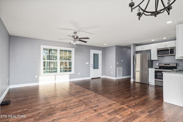 kitchen featuring white cabinetry, stainless steel appliances, light stone counters, dark hardwood / wood-style floors, and ceiling fan with notable chandelier