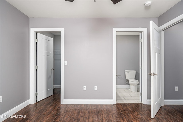 unfurnished bedroom featuring ensuite bath, dark wood-type flooring, and a closet