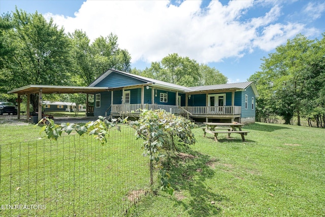 rear view of house featuring a carport, a porch, and a yard