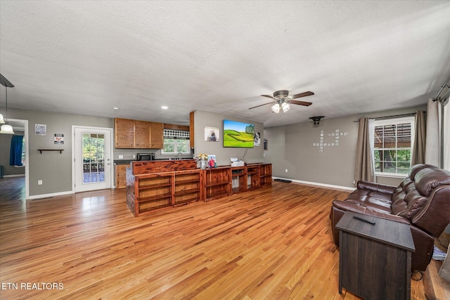 living room featuring a textured ceiling, light hardwood / wood-style flooring, and ceiling fan