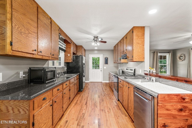 kitchen with appliances with stainless steel finishes, light hardwood / wood-style floors, ceiling fan, and sink