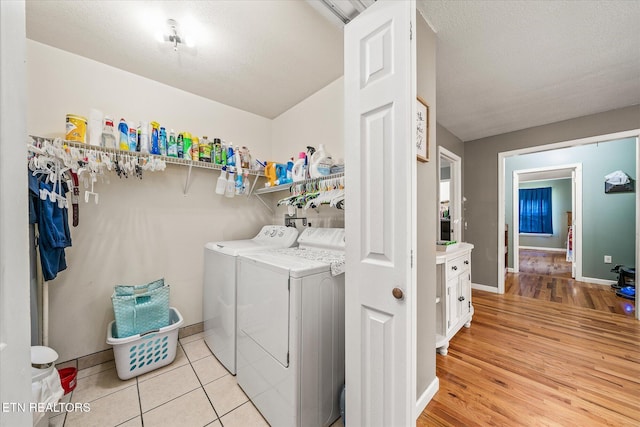 laundry room with light tile patterned floors, a textured ceiling, and washing machine and clothes dryer