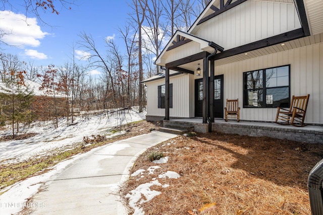 snow covered property entrance featuring covered porch