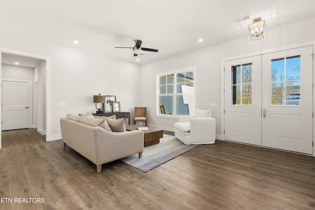 living room with ceiling fan with notable chandelier and wood-type flooring