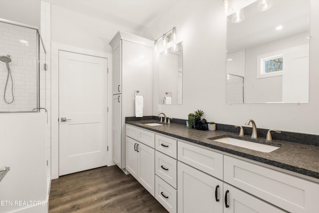 bathroom with wood-type flooring, a shower with shower door, and vanity