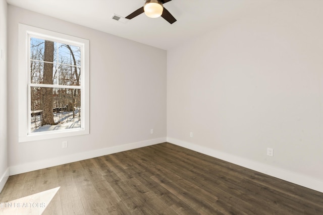 empty room featuring baseboards, visible vents, ceiling fan, and dark wood-style flooring