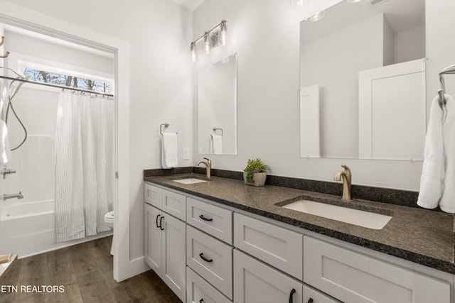 full bath with double vanity, wood finished floors, a sink, and shower / tub combo with curtain