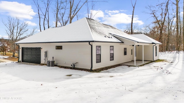 view of snow covered exterior with cooling unit and a garage