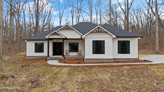 view of front of home with a porch, a front yard, and a shingled roof